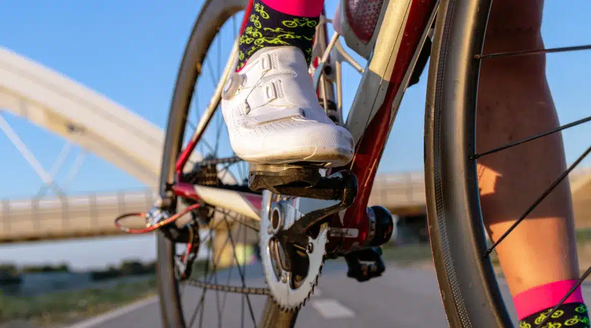 Close-up of a cyclist’s shoe clipped into the pedal, wearing colourful socks, showing the quality and detail of custom cycling clothing by TD Sportswear.