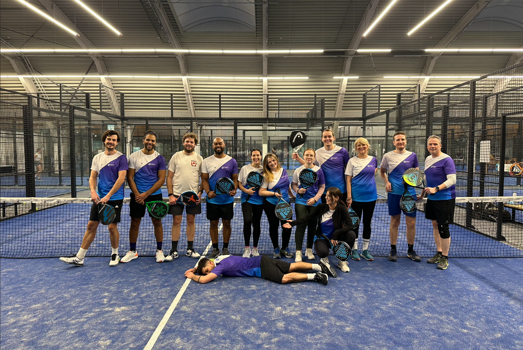 Padel en tennis shirts ontwerpen en bedrukken met eigen logo en ontwerp - klant foto paars wit blauw shirt op padel baan team